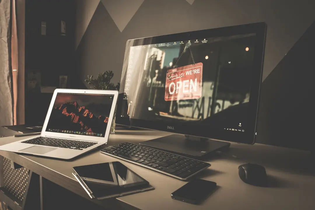 A tidy desk with a laptop and monitor, where a business's marketing system is planned